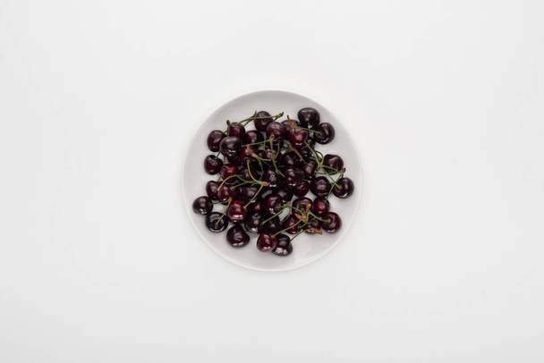 top view of red and ripe cherries on white plate  - Fotoğraf, Görsel
