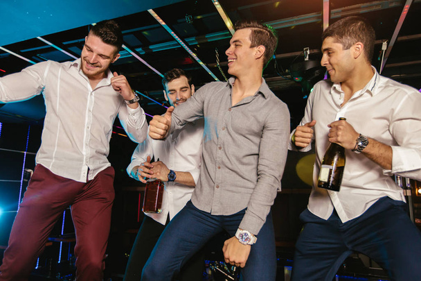 Група усміхнених друзів-чоловіків розважаються в нічному клубі
  - Фото, зображення