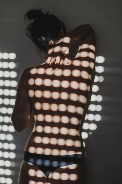  naked woman ,back view . sun is coming through the window. Indoors lifestyle - Photo, image