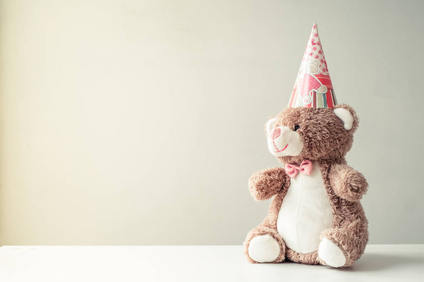 Oso de juguete hecho a mano en el capó para un cumpleaños en un fondo gris
 - Foto, imagen