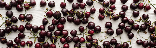 panoramic shot of fresh, sweet, red and ripe cherries with droplets on wooden table  - 写真・画像