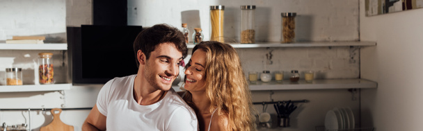 panoramatický záběr šťastného usmívajícího se páru v kuchyni - Fotografie, Obrázek