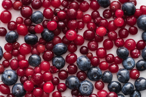 top view of red, fresh and ripe cranberries and whole blueberries  - Foto, afbeelding