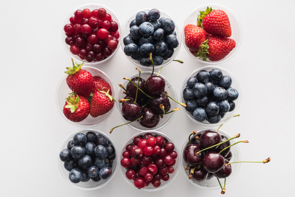 pohled na celé brusinky, jahody, borůvky a třešně v plastových kelímcích  - Fotografie, Obrázek