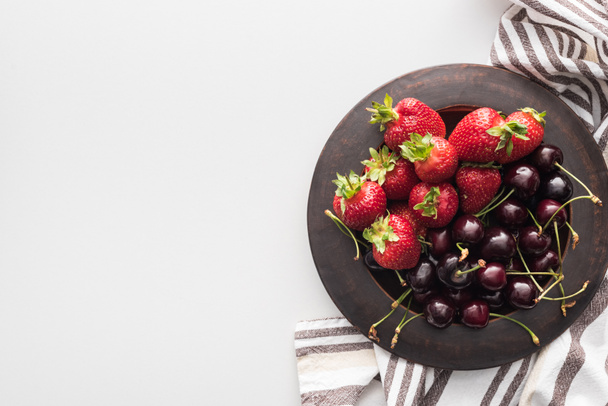 top view of whole strawberries and sweet cherries on plate  - Foto, imagen