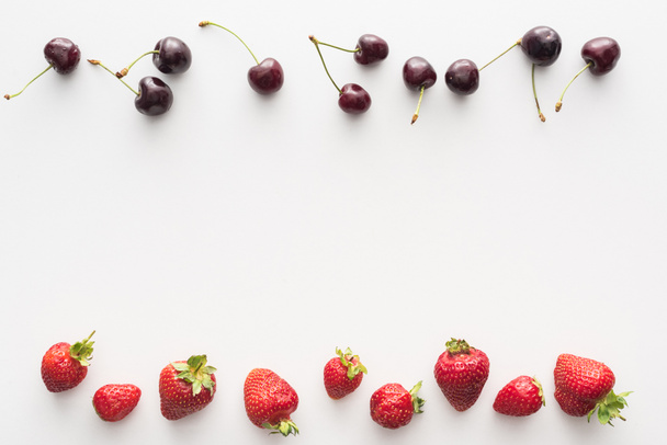 top view of sweet, fresh cherries and red strawberries on white background  - Foto, imagen