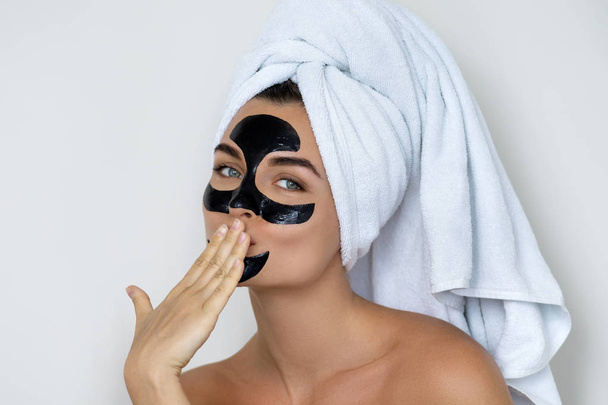 Young and beautiful woman with black peel-off mask on her face  - Foto, afbeelding