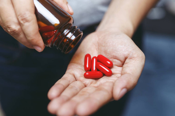 perto mão homem segurando um medicamento, com derrama as pílulas de vitamina fora da garrafa. Cuidar dos cuidados de saúde
 - Foto, Imagem
