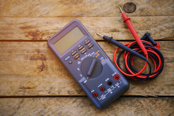 digital multimeter and wiring on wooden table. special tools of technician for work with circuit and electrical. technician use the digital multimeter in workshop for check and repair equipment. - Photo, Image