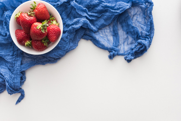 vue de dessus des fraises sucrées et entières sur bol avec chiffon bleu
  - Photo, image