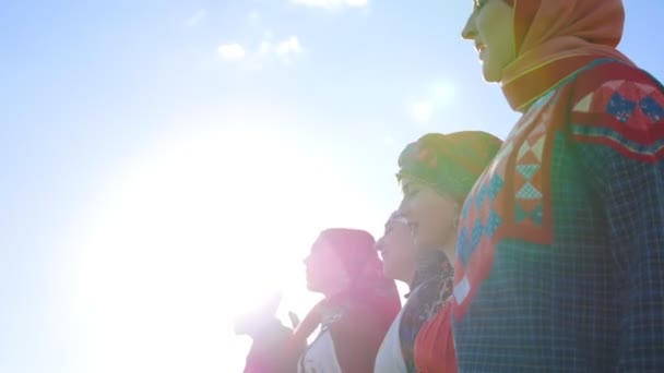 Lidé v tradičních lidových šatech, stojící v řadě na hřišti a zpívající píseň - Záběry, video