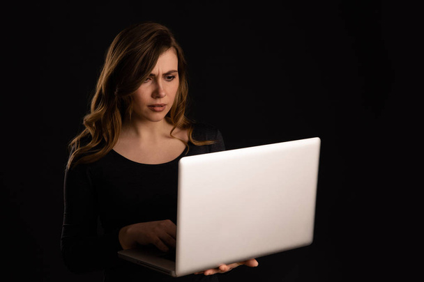 Nervous and upset young woman with laptop getting problems. Bad news on the screen. - Foto, imagen