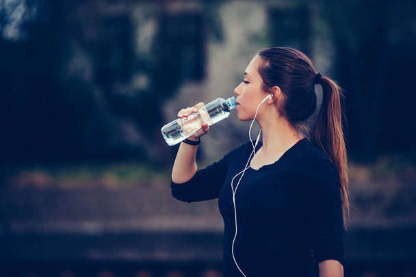 Бегунья, стоящая у реки с бутылкой воды
 - Фото, изображение