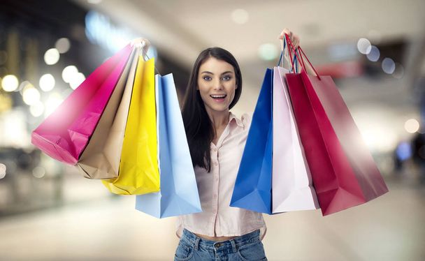 Gelukkige vrouw met shopping tassen in de hand - Foto, afbeelding