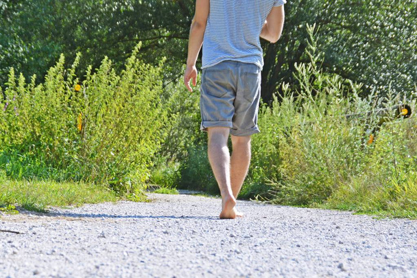 足のクローズアップ - 森の中の小石のパスを横切って歩き、夏の温度で自然の中でリラックス - 写真・画像