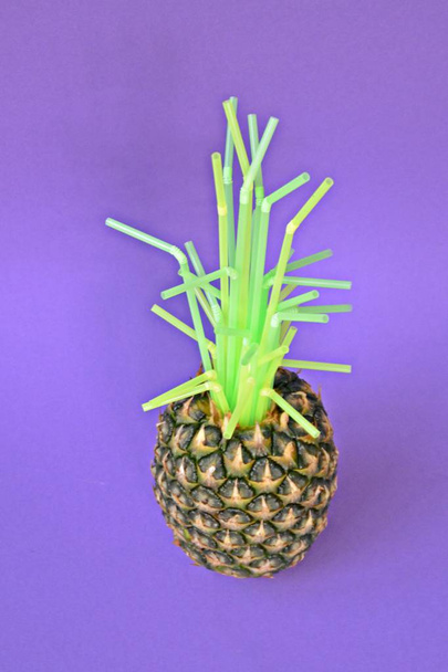 Het groen van de ananas wordt vervangen door plastic rietjes-een concept dat laat zien hoeveel plastic is al in de natuur-kunst tegen een monochrome achtergrond - Foto, afbeelding