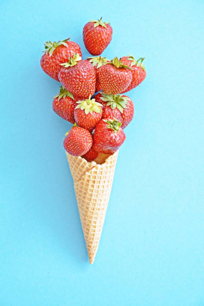 Ice cream cone with strawberries on a colored background - - Foto, imagen