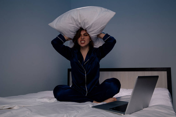 Mulher estressada na cama segurando um travesseiro na mão
. - Foto, Imagem