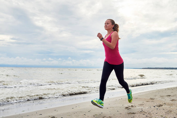 junge Fitness-Läuferin läuft am Meer, kopiert Raum. Mädchen  - Foto, Bild