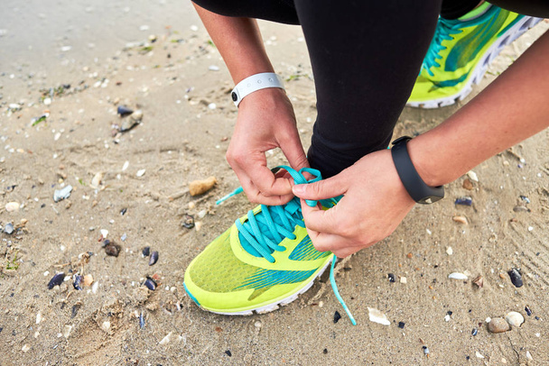 Mujer atando cordones para correr preparándose para correr en la playa del océano
, - Foto, imagen