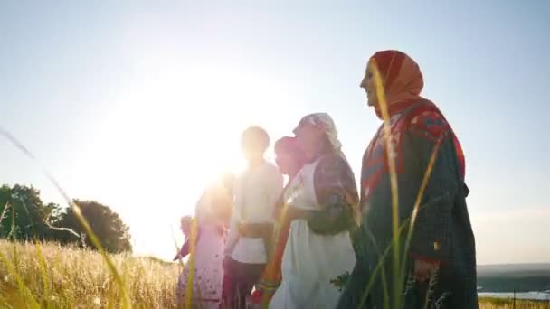 Ženy a muži v tradičních ruských folklórních šatech v řadě na poli a zpívající píseň-jasný slunný letní den - Záběry, video