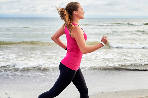 Young fitness woman runner running at seaside, copy space. Girl  - Φωτογραφία, εικόνα
