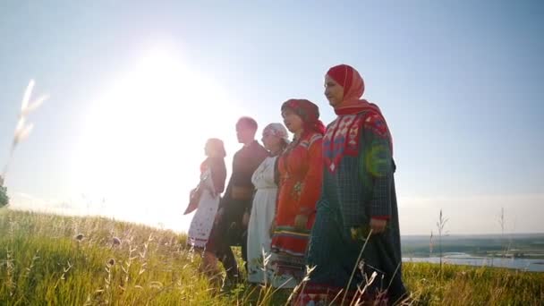 Mujeres y hombres con ropa tradicional rusa caminando en fila en el campo y cantando una canción
 - Imágenes, Vídeo