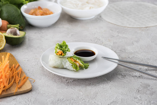 tasty and served spring rolls with soy sauce on white plate with metal sticks  - Photo, Image