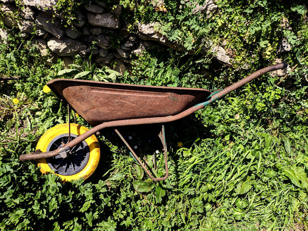 Stare taczki z żółtym kółkiem na trawie - Zdjęcie, obraz