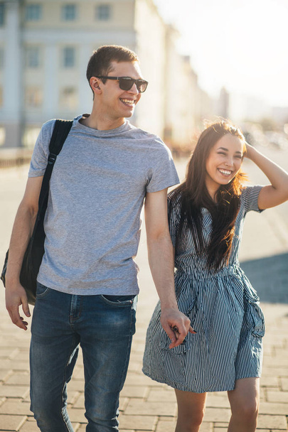 愛ティーンエイジャーの友人の幸せな若いカップルは、街の通りで一緒に歩くカジュアルなスタイルで服を着て - 写真・画像