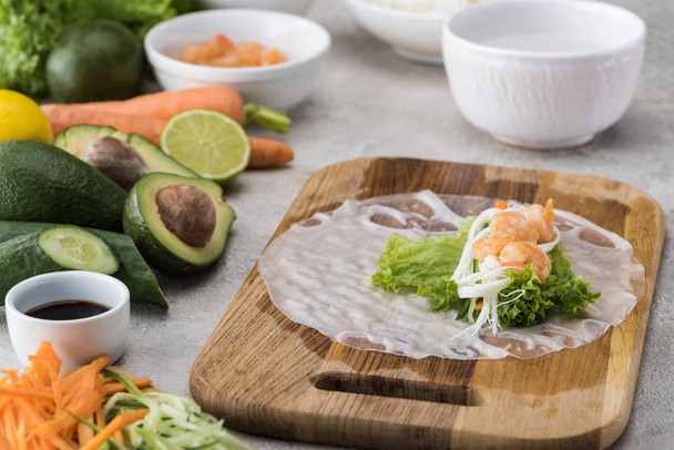 Salat, Nudeln und Garnelen auf Reispapier, auf Schneidebrett   - Foto, Bild