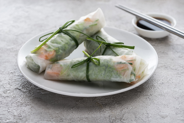 tasty and served spring rolls with on white plate with soy sauce and metal sticks  - Photo, Image