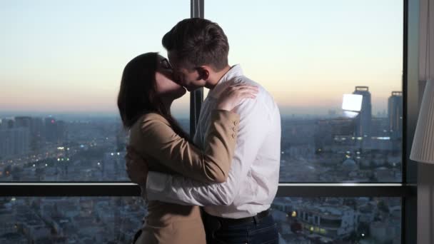 Para, mężczyzna i kobieta tańczą i całują się w pobliżu panoramicznego okna z widokiem na miasto. - Materiał filmowy, wideo