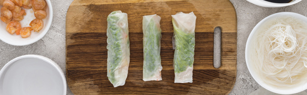 panoramic shot of spring rolls on cutting board among ingredients  - Photo, Image