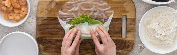 panoramic shot of woman making roll on cutting board among ingredients  - Photo, Image