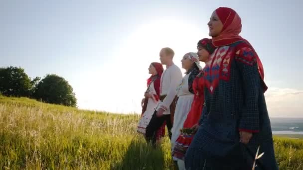 Ženy a muži v tradičních ruských folklórních šatech v řadě na hřišti a zpívající píseň - Záběry, video