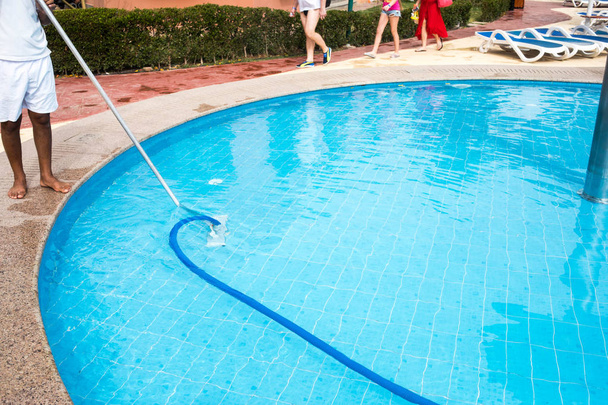 Homem limpando uma piscina no verão. Limpador da natação
  - Foto, Imagem