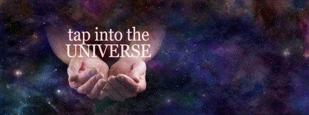 Profiteer van de kracht van het universum-mannelijke gecupt handen die uit de hemelse diepe ruimte komen met de woorden Tik in het universum zwevend boven op een kosmische nachtelijke hemel achtergrond - Foto, afbeelding