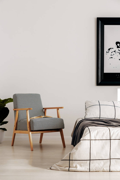 Grey retro armchair in white bedroom interior with wooden accents - 写真・画像