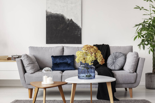Flowers in blue glass vase on wooden coffee table in elegant living room interior - Fotó, kép