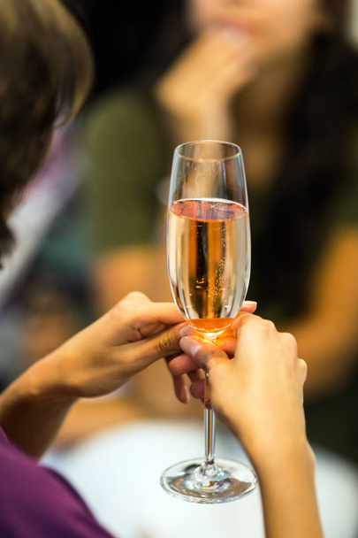 female hands holding glass of champagne on blurred background - Photo, Image