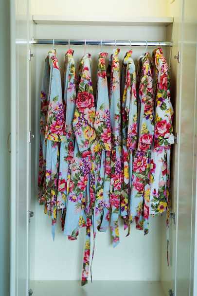 belas vestes de seda com padrão floral colorido pendurado no guarda-roupa
 - Foto, Imagem