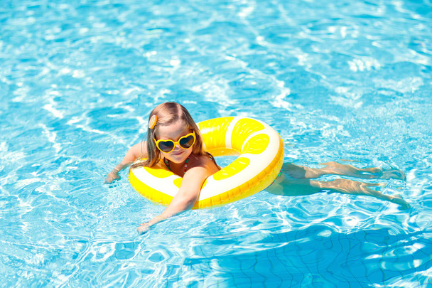 Child in swimming pool on ring toy. Kids swim. - Фото, изображение