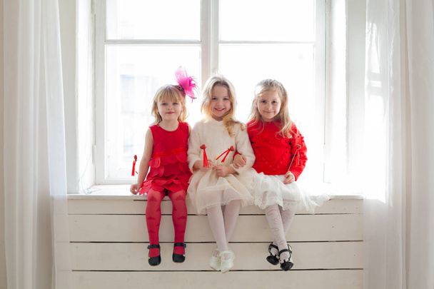 赤いハート風船で座っている3人の小さな女の子 - 写真・画像