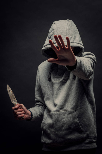 A man with a knife covers his face with his hand in the Studio o - Photo, image