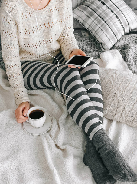 κορίτσι σπίτι ρούχα smartphone φλιτζάνι καφέ κρεβάτι - Φωτογραφία, εικόνα