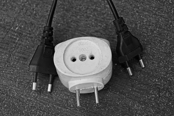 Witte socket adapter en twee elektrische stekkers op de tafel - Foto, afbeelding