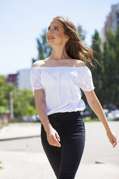 Young beautiful brunette woman in jeans and white blouse walking - Foto, Bild