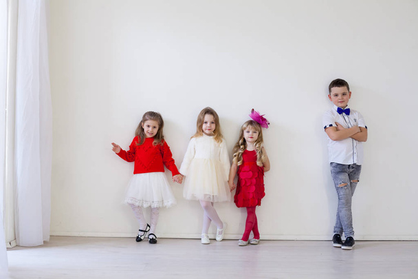 Poika ja kolme pientä tyttöä seisovat valkoisella seinällä.
 - Valokuva, kuva