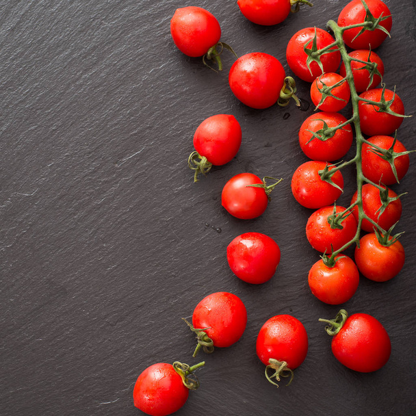 świeże pomidory cherry rozproszone na czarnej płycie z łupków - Zdjęcie, obraz
